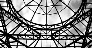 Black and white abstract view of a steel structure canopy with cloudy sky.