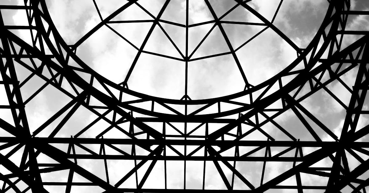 Black and white abstract view of a steel structure canopy with cloudy sky.
